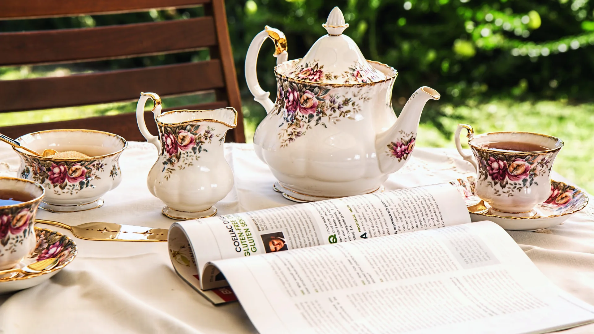 A cozy terrace setup with a blue teacup, a wooden table, afternoon tea treats, and an open book — highlighting the benefits of afternoon tea.
